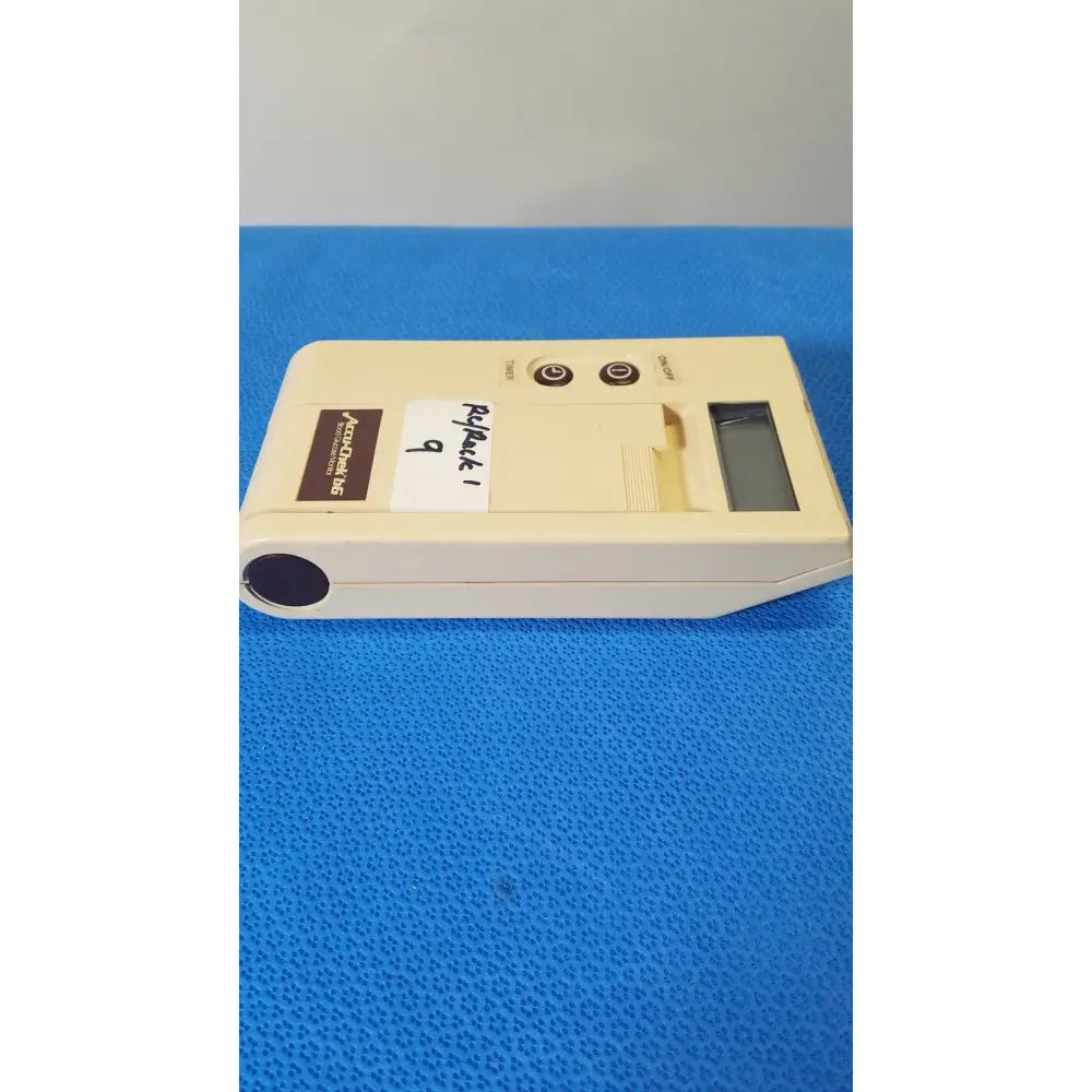 Cream-colored bio-dynamics accu-chek bg blood glucose monitor with digital display, buttons, and test strip slot