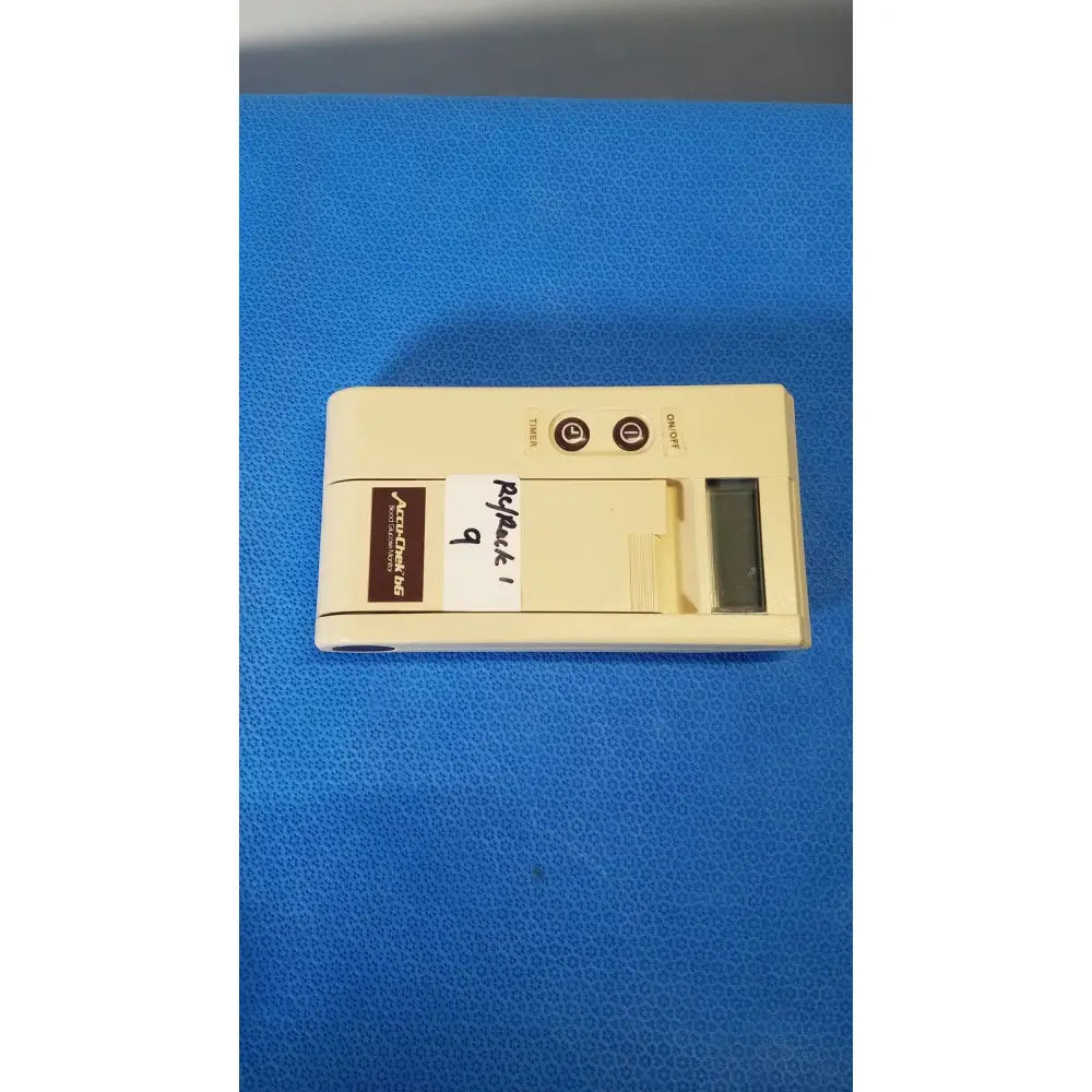 Beige plastic Bio-Dynamics Accu-Chek bG blood glucose monitor with two circular buttons and a small rectangular screen