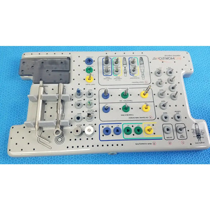 Gray plastic surgical instrument tray with organized compartments holding blue green yellow and silver tools for tapered internal dental implant surgery kit