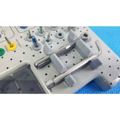 Silver tapered internal dental handpiece with textured grip and measurement markings on gray surgical tray in kit
