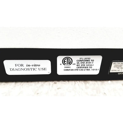 Black rectangular instruments elx800 universal microplate reader showing white certification labels on its back side