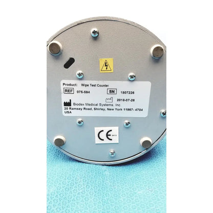 Gray metallic circular biodex medical systems wipe test counter with white label showing product info and certification marks
