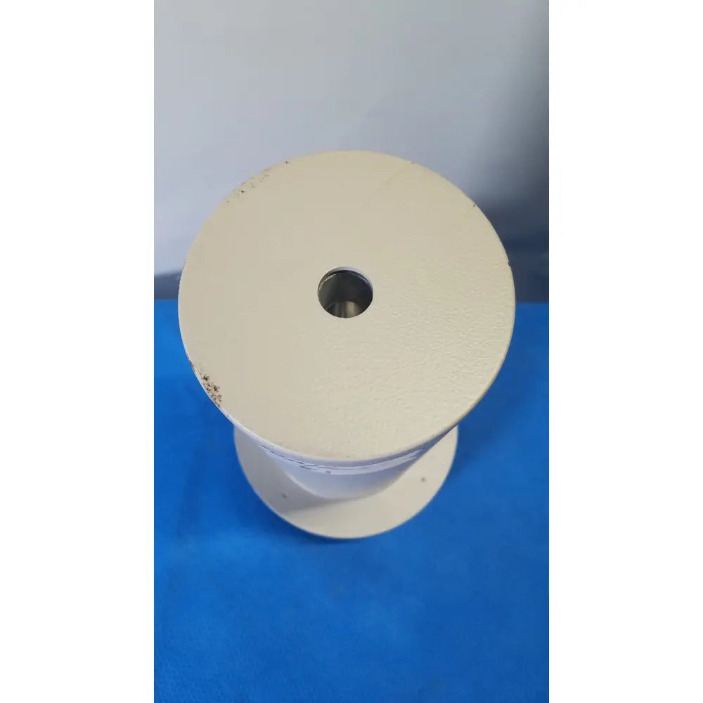 Off-white industrial spool with central hole and textured surface for reuse medical applications in biodex well counter 187-602