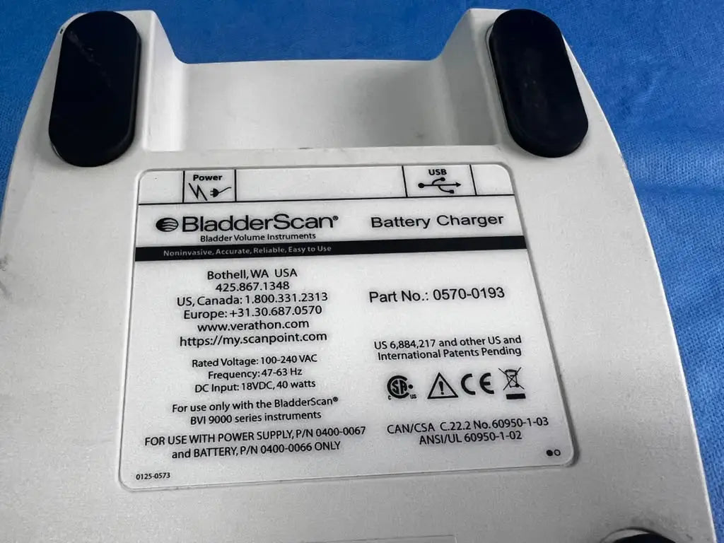 White plastic bladderscan battery charger with black rubberized footpads and detailed specification label for reuse medical use