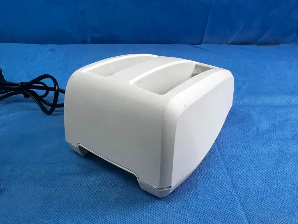 White plastic two-slot toaster with black power cord for bladderscan battery charger reuse medical applications