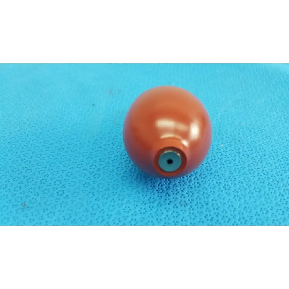 A glossy orange blood pressure inflation bulb pump with a metallic blue valve hole at its base for pressure inflation
