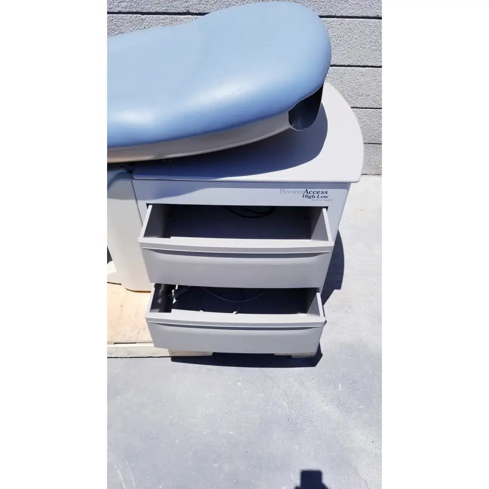 Light blue padded brewer access high-low exam table with white base and three drawers for medical use