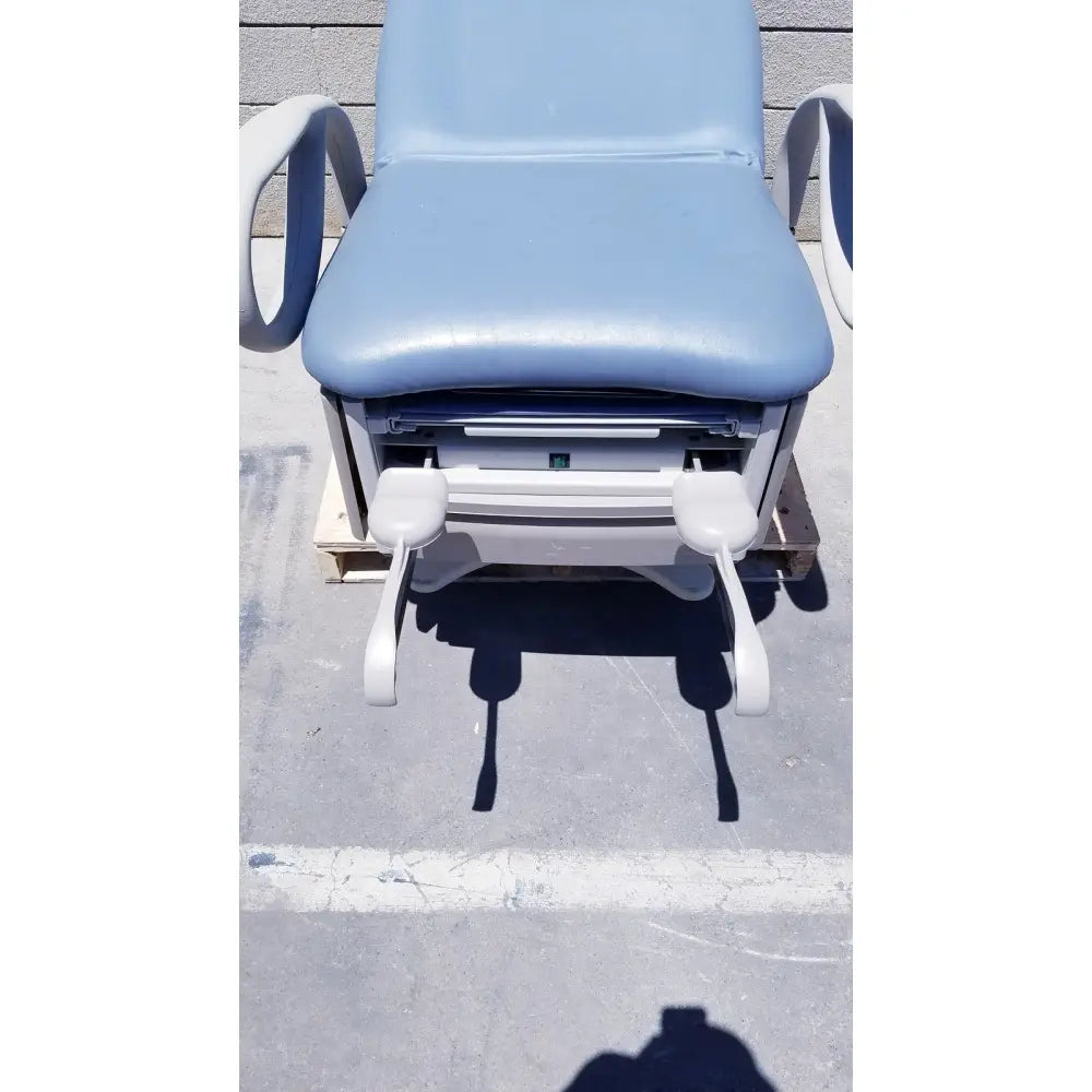 Light blue padded brewer access high-low exam table with white plastic arms and footrests for medical use