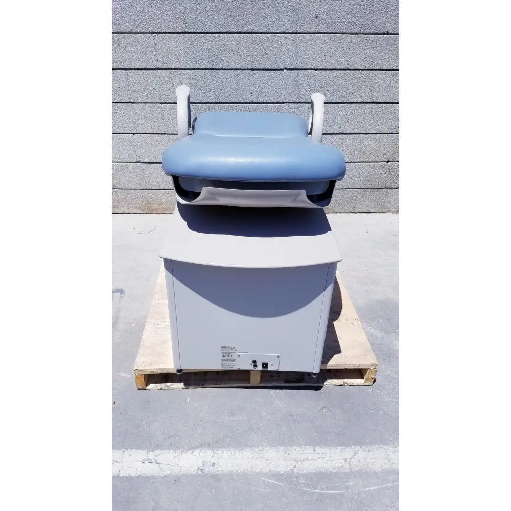 Brewer Access high-low exam table with light blue padded top, white armrests, gray base on wooden pallet