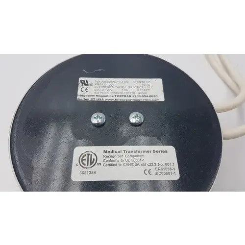 Black circular medical transformer with silver screws and white labels from bridegeport magnetics tortran ip600 for reuse medical