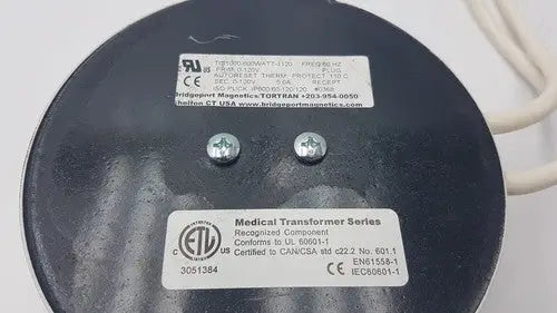 Black circular medical transformer with silver screws and white labels from bridegeport magnetics tortran ip600 for reuse medical