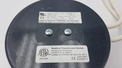 Black circular medical transformer with silver screws and white labels from bridegeport magnetics tortran ip600 for reuse medical