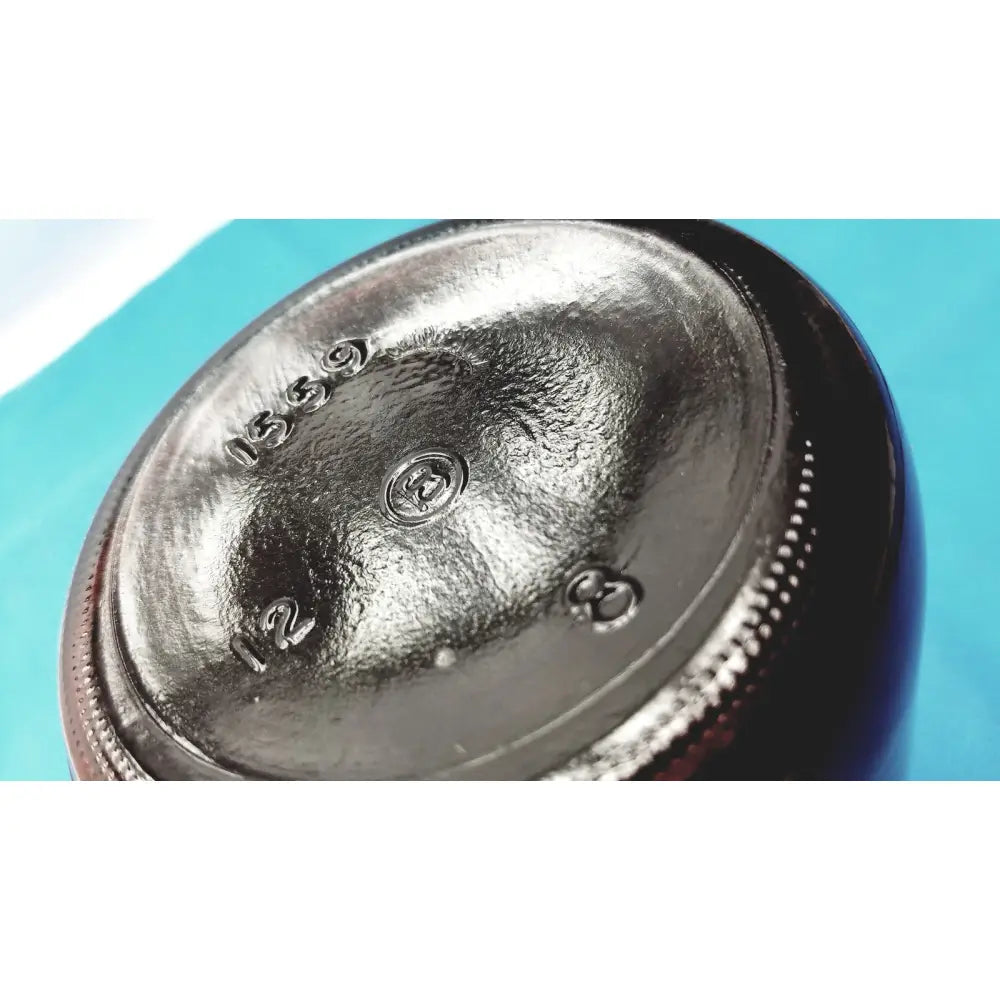 Bottom view of a dark glossy brown glass chemical bottle with embossed markings and circular logo for reagent storage lab use