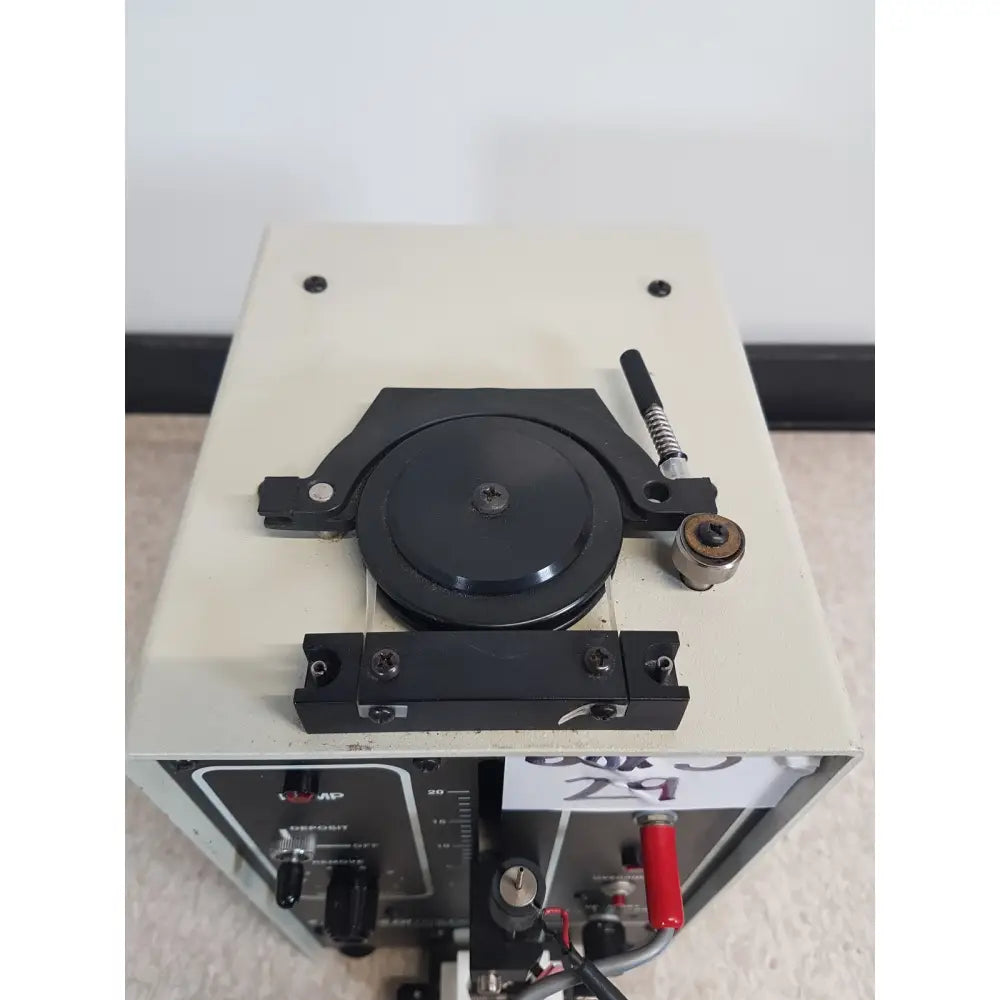 Black circular component with central screw mounted on a metal frame of buchler instruments auto densi-flow II C density fractionator