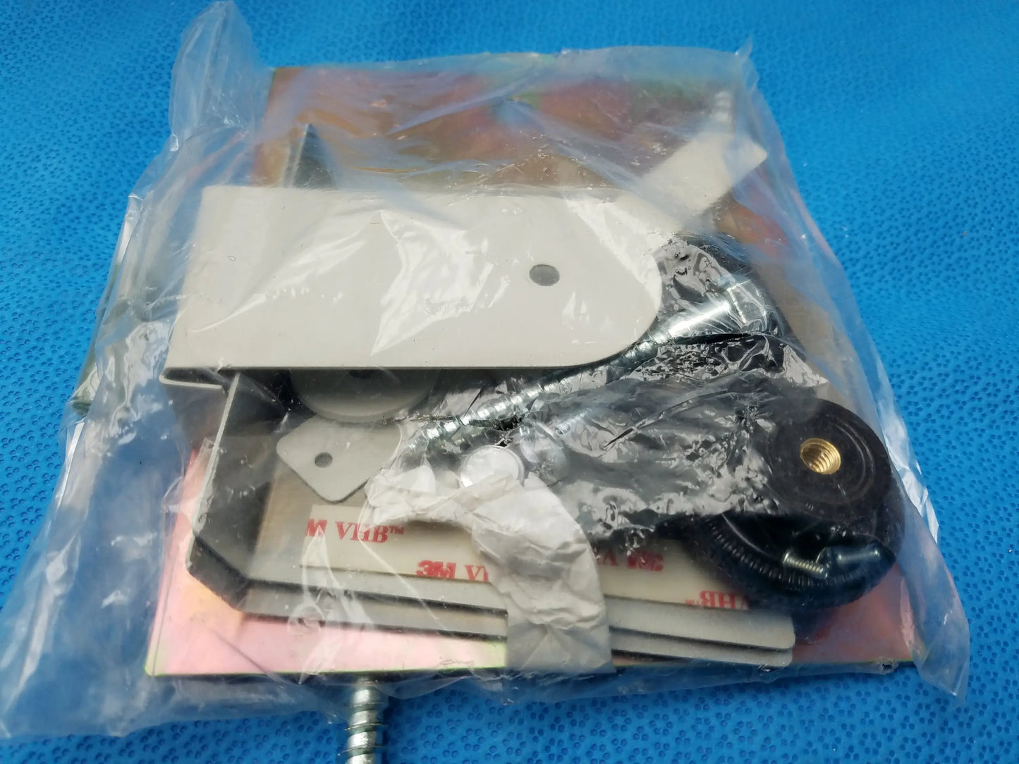 White plastic mounting bracket with metal hardware components inside a clear bag for smiths medical equipment reuse