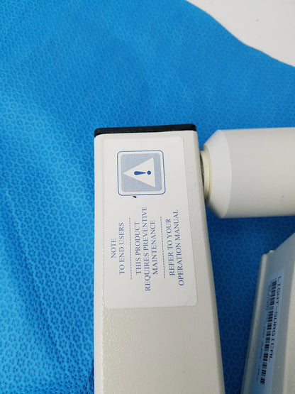 White rectangular burton medical outpatient ii coolspot ii examination light with black top edge and maintenance label for reuse medical equipment
