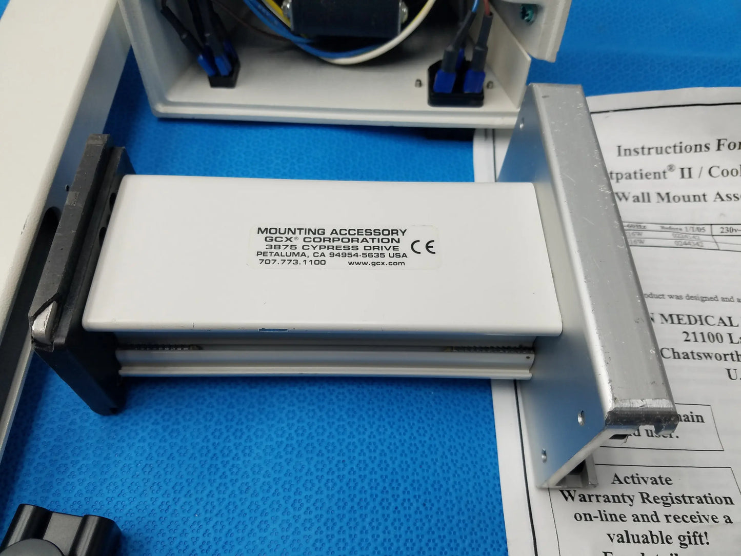 White rectangular mounting accessory with black text and CE mark by gcx corporation for burton medical examination light wall mount assembly