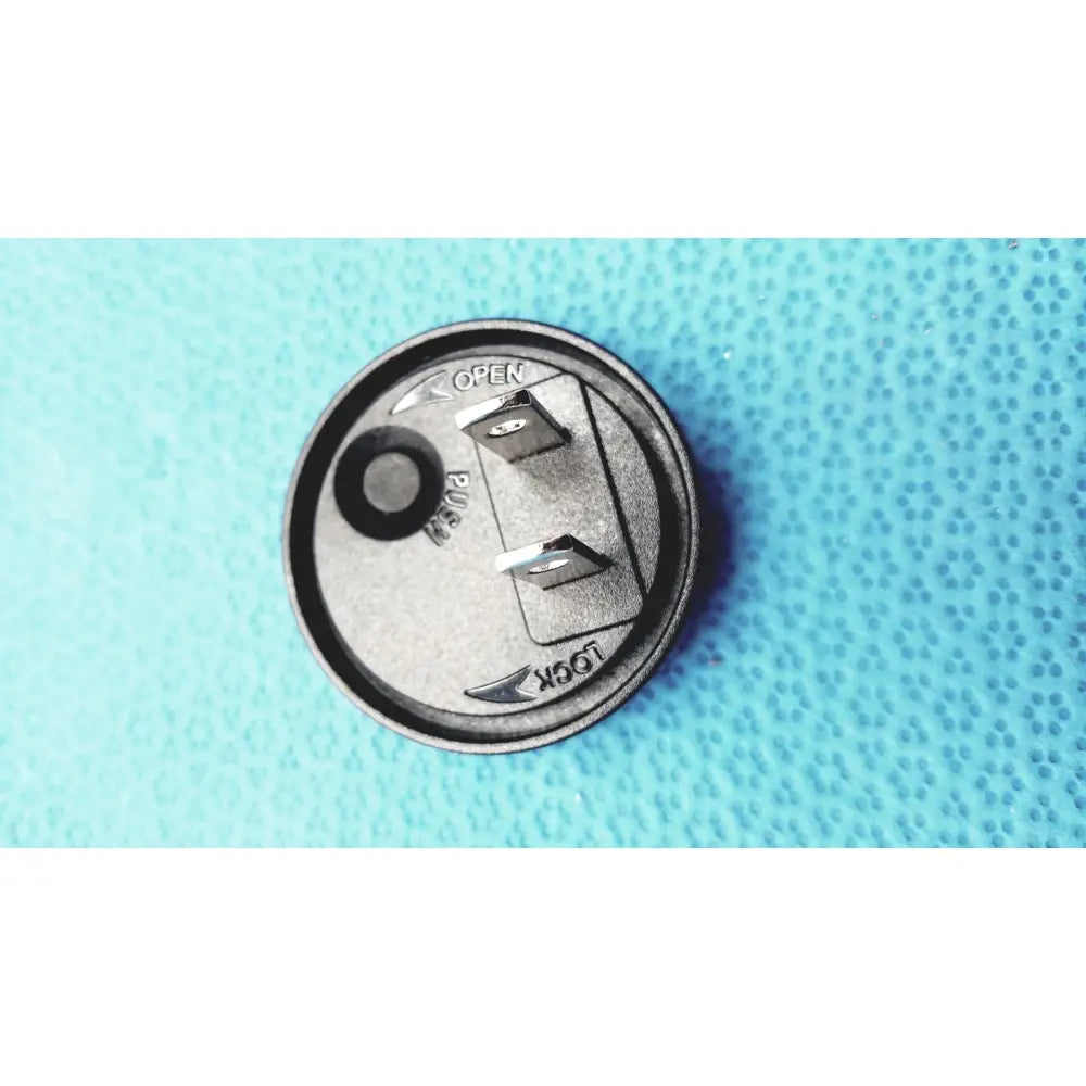 Black circular power switch with metallic prongs and open lock labels on the back of burton ultraviolet examining light