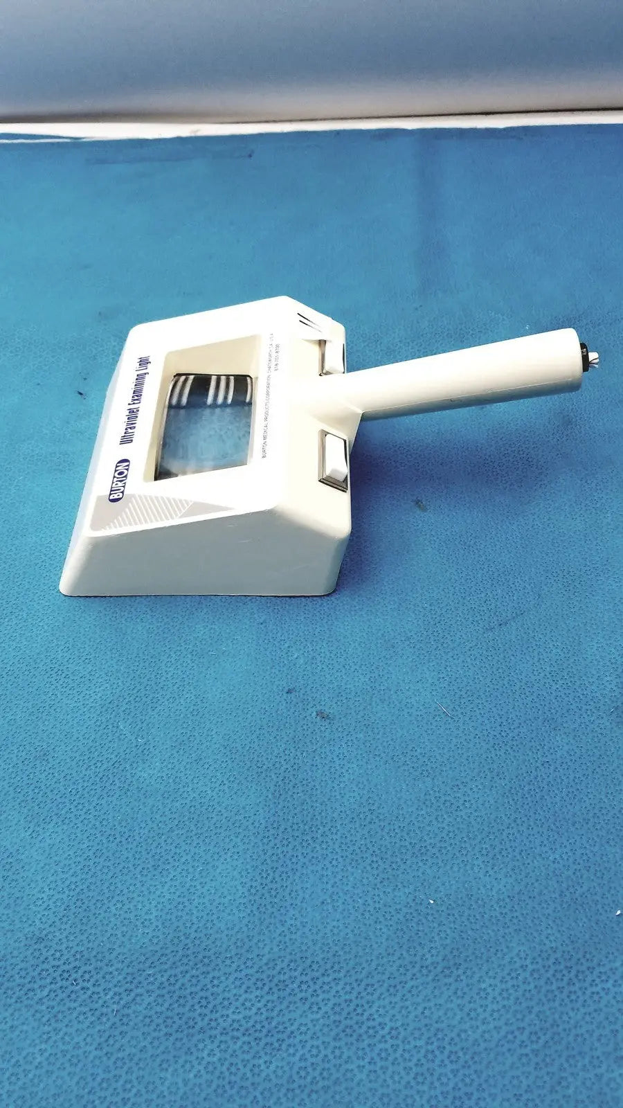 White plastic burton ultraviolet examining light with rectangular base handle and adjustable focus knob