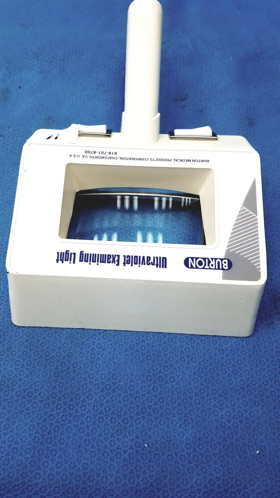 Burton ultraviolet examining light 31601 with white vertical handle and rectangular window showing blue uv light strips