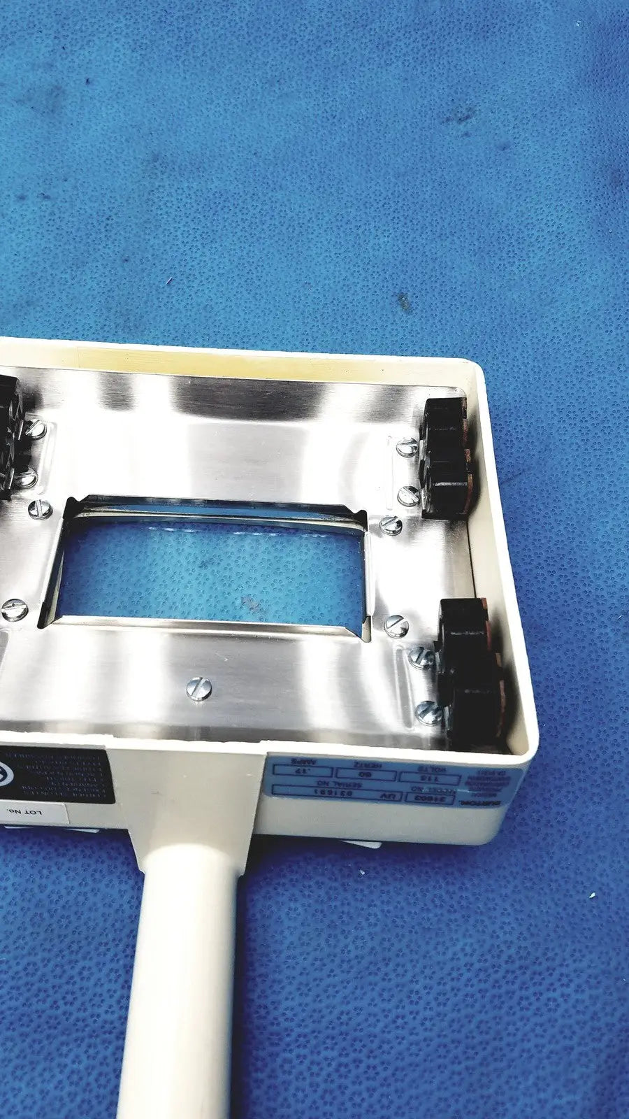 White plastic-handled burton ultraviolet examining light with metallic silver top plate and blue labeling for medical use