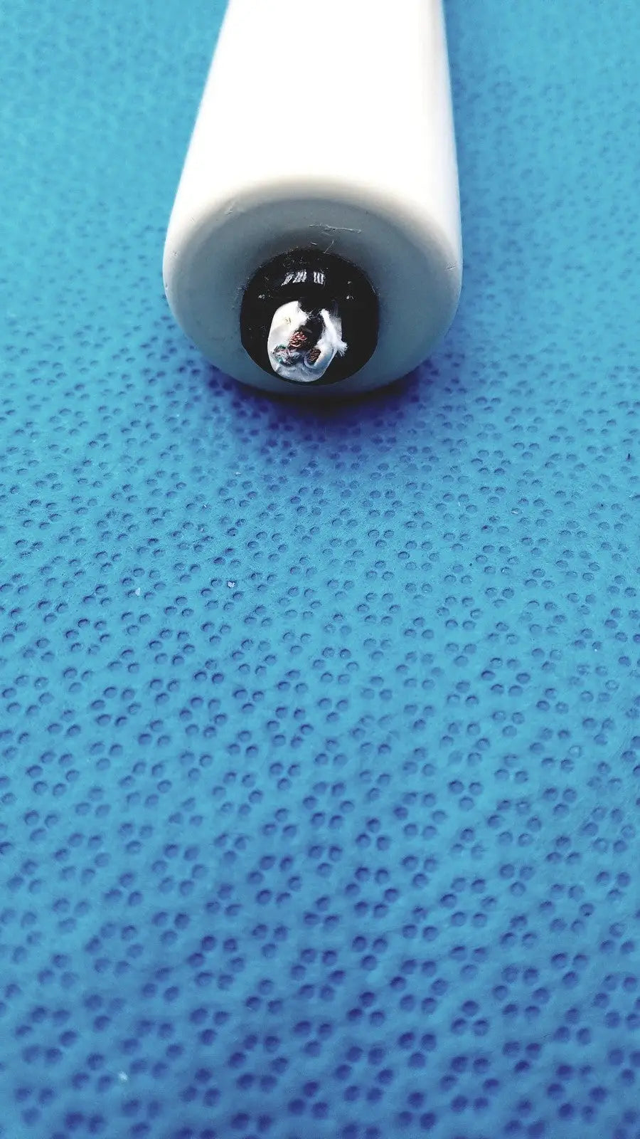 White pen with shiny metallic tip used with Burton ultraviolet examining light for precise ultraviolet examining tasks