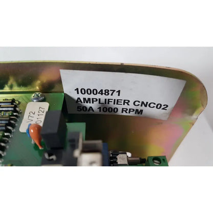A white label with black text on a metallic iridescent surface above green circuit board components of bystronic amplifier cnco2 50a