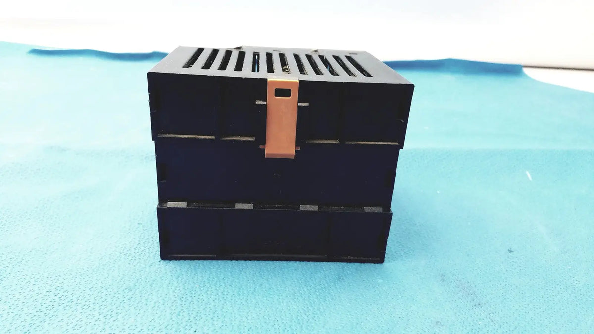 Black Bystronic modul input output box with copper-colored latch and horizontal slits on top for input output module use