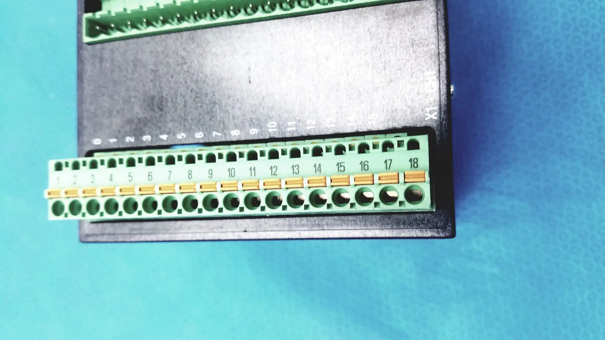 Green terminal block with numbered gold contacts on black Bystronic modul input output industrial control panel