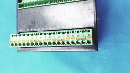 Green terminal block with numbered gold contacts on black Bystronic modul input output industrial control panel