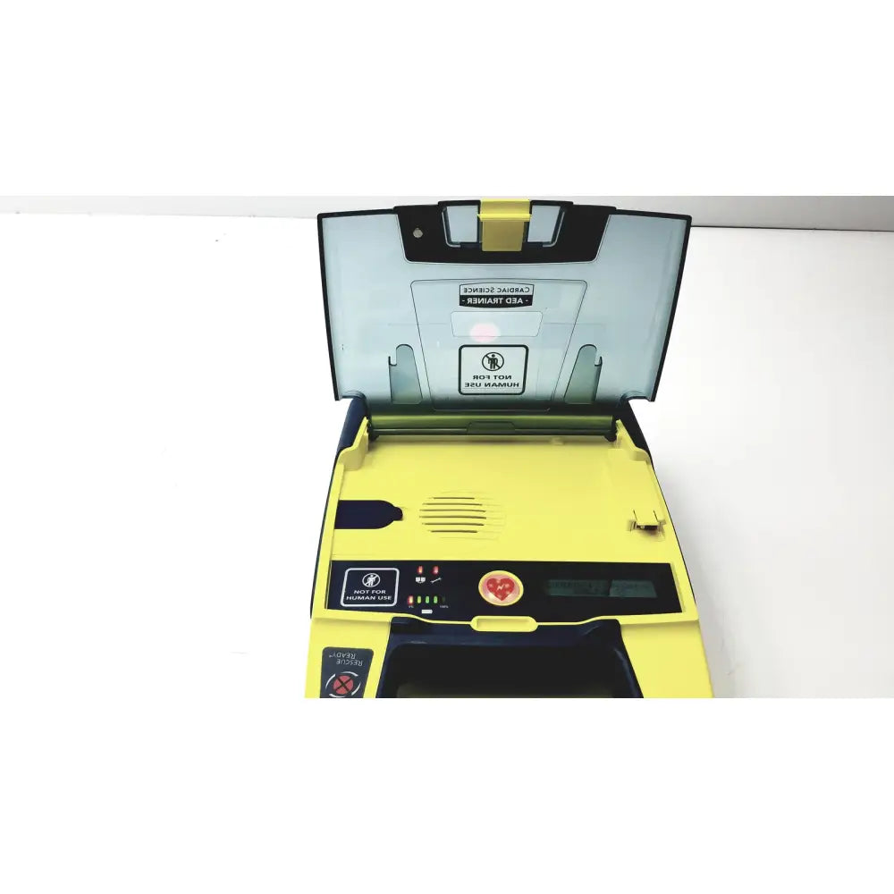 Yellow and black cardiac science aed trainer teaching device with clear lid and control panel featuring indicator lights and heart button