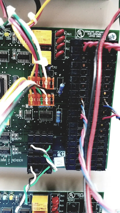 Green circuit board of cardkey s300-xl access control panel controller with red black switches yellow capacitors and wires