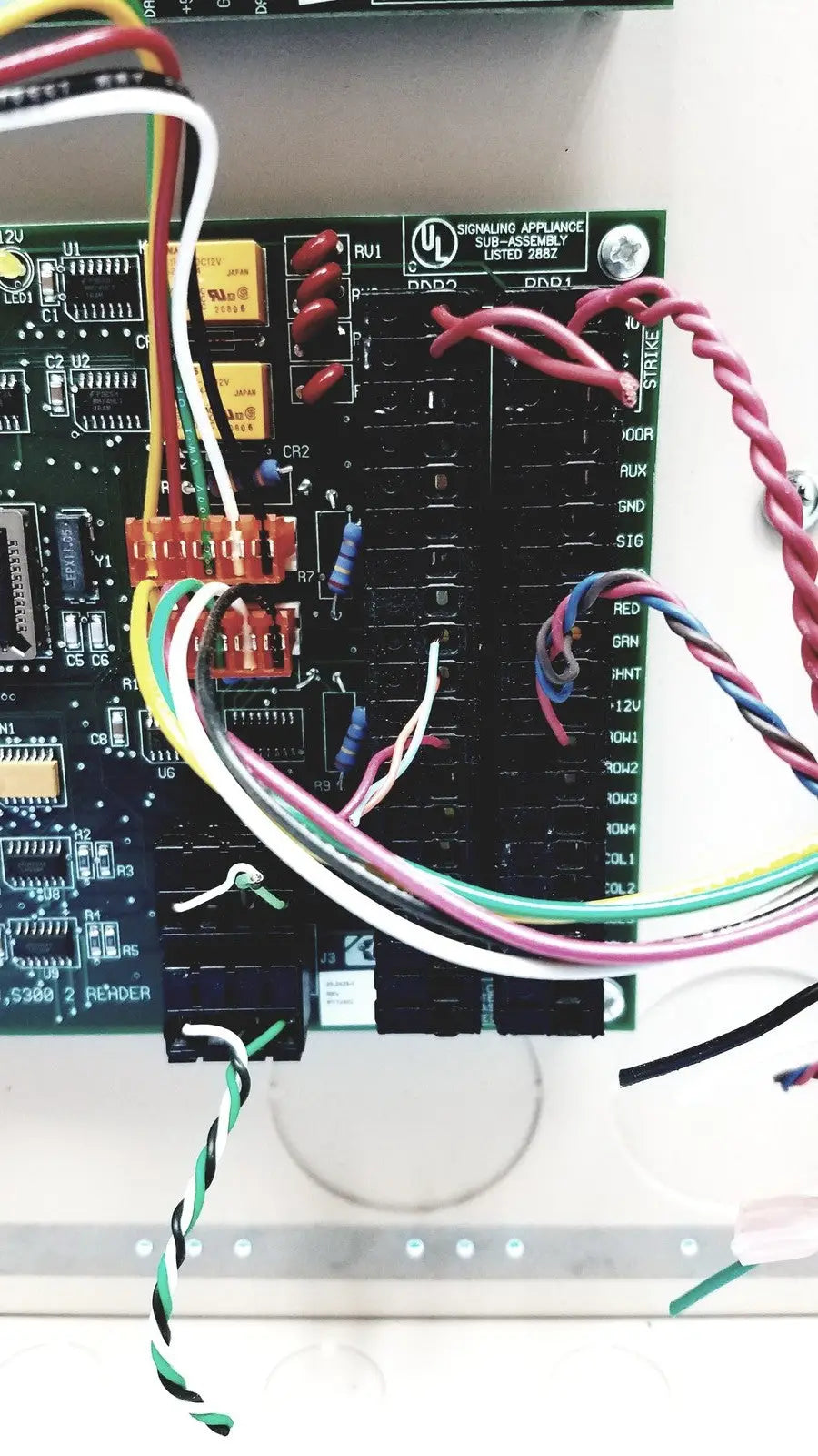 Black circuit board with colorful wires connected to orange terminal blocks on cardkey s300-xl access control panel controller