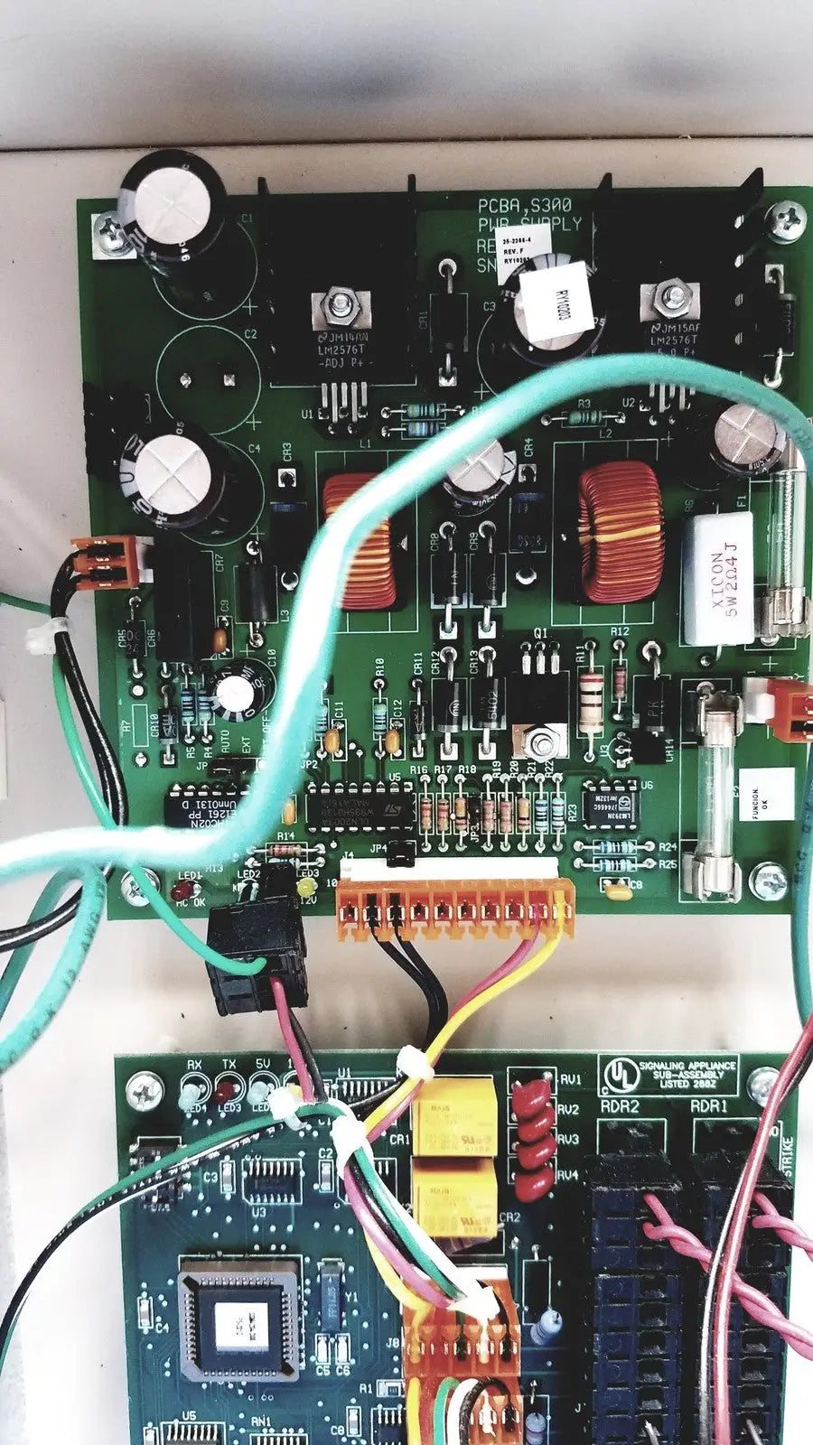 Green printed circuit board with electronic components and light blue cable in cardkey s300-xl access control panel controller