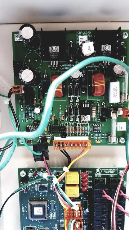 Green printed circuit board with electronic components and light blue cable in cardkey s300-xl access control panel controller