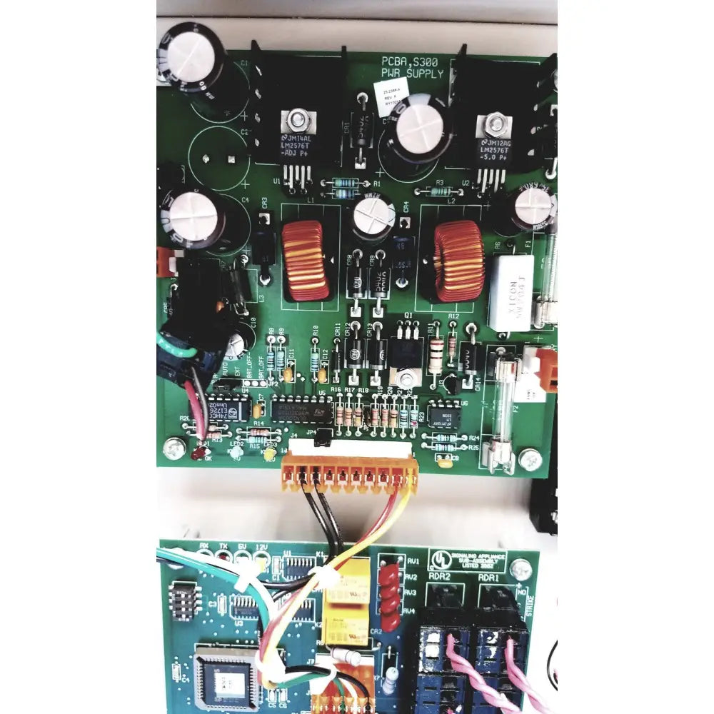 Green printed circuit board with black capacitors and red toroidal inductors in s300-xl access control panel controller