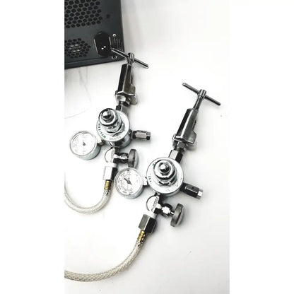 Two chrome-finished western medical gas regulators with pressure gauges and braided hoses on carefusion vmax encore analyzer