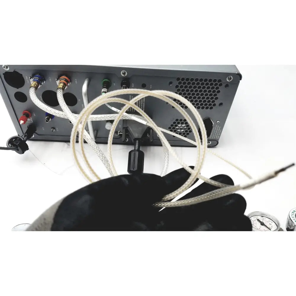 A gloved hand holds a coiled white braided cable with metallic connectors for carefusion vmax encore analyzer use