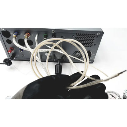 A gloved hand holds a coiled white braided cable with metallic connectors for carefusion vmax encore analyzer use