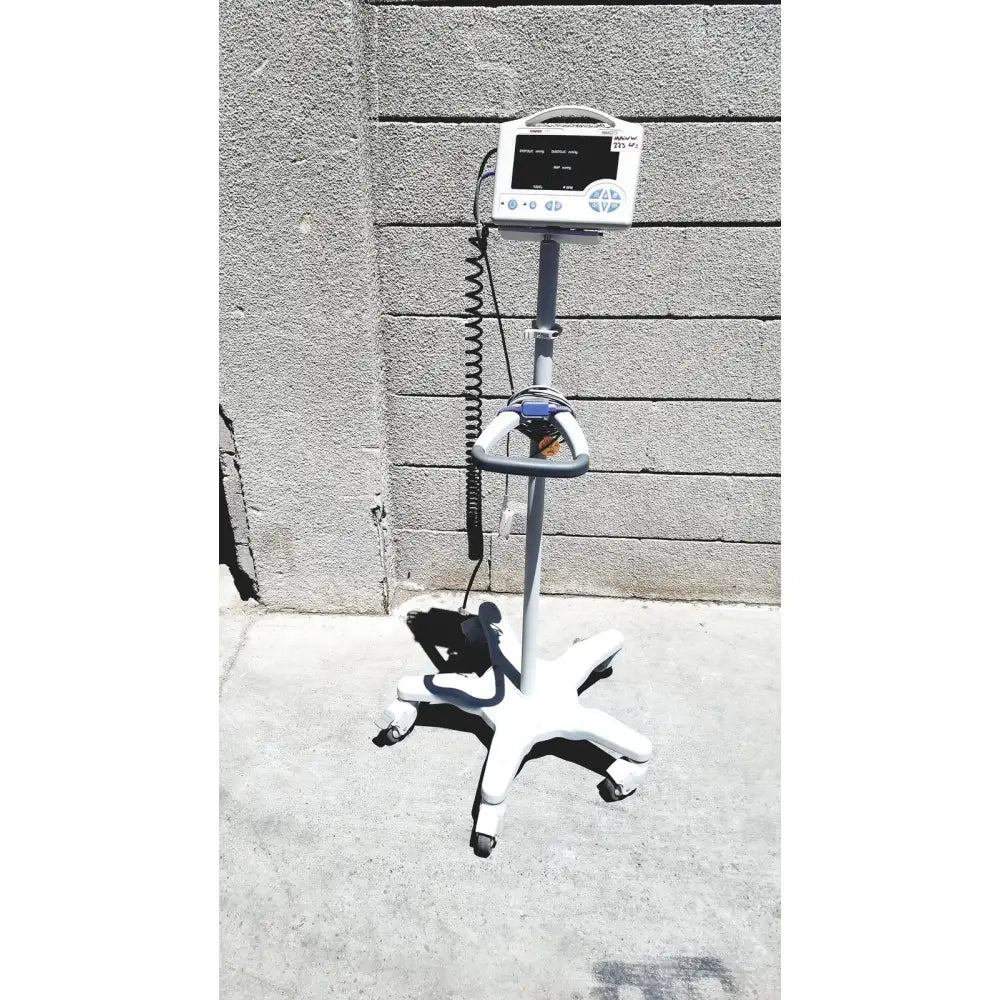 White CASMED 740 vital signs monitor with gray accents and sp02 finger probe mounted on wheeled rolling stand with black cables