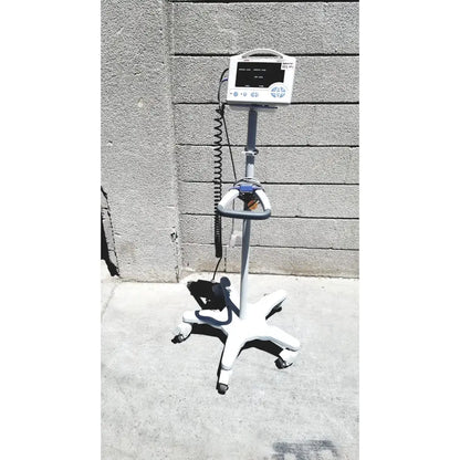 White CASMED 740 vital signs monitor with gray accents and sp02 finger probe mounted on wheeled rolling stand with black cables