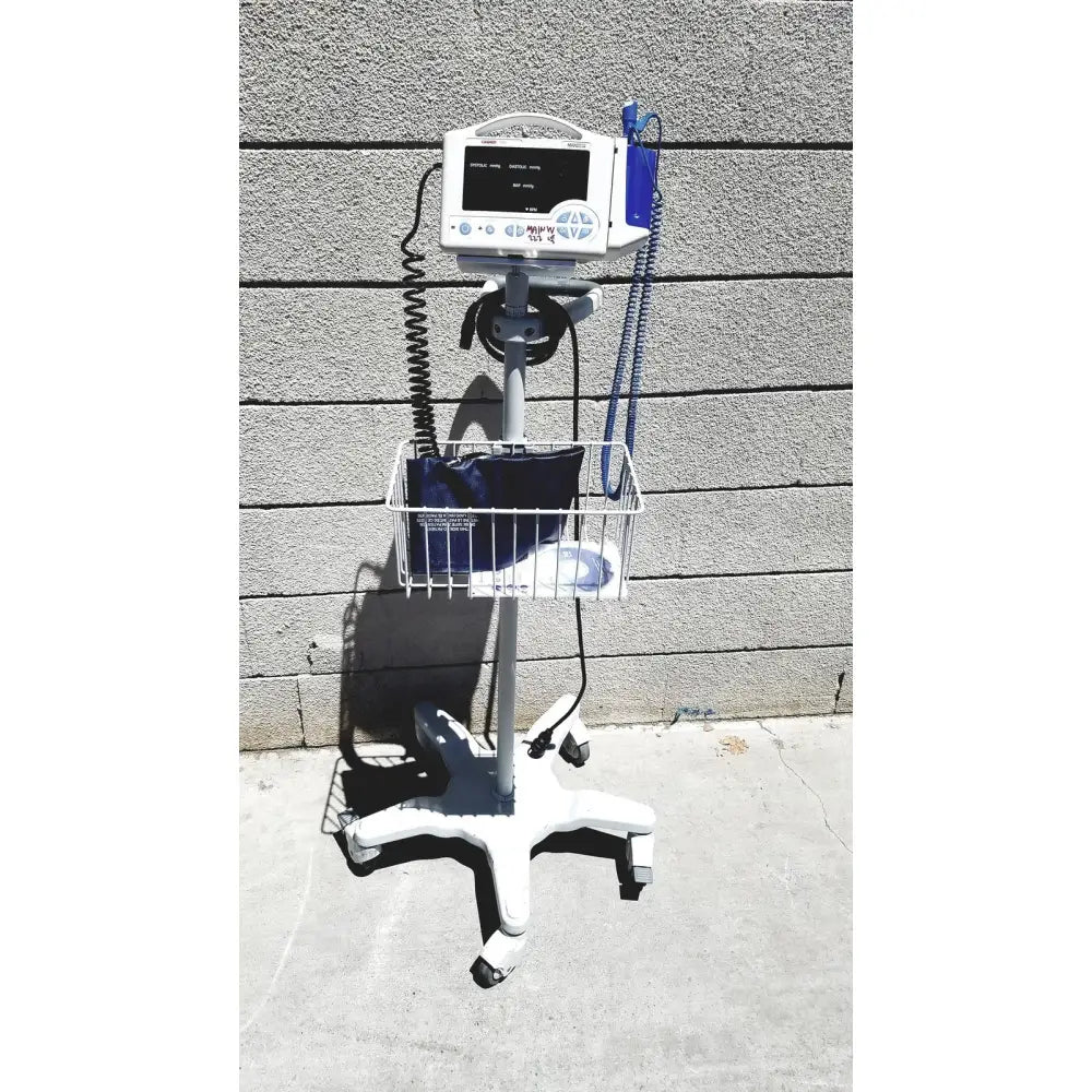 White casmed 740 vital signs monitor mounted on wheeled rolling stand with wire basket for medical supplies