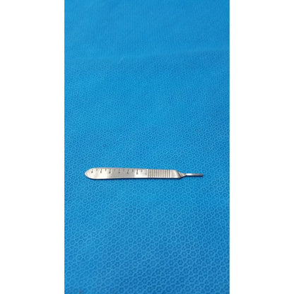 A metallic centurion pakistan scalpel with ruler-etched blade and textured handle resting on a blue surface