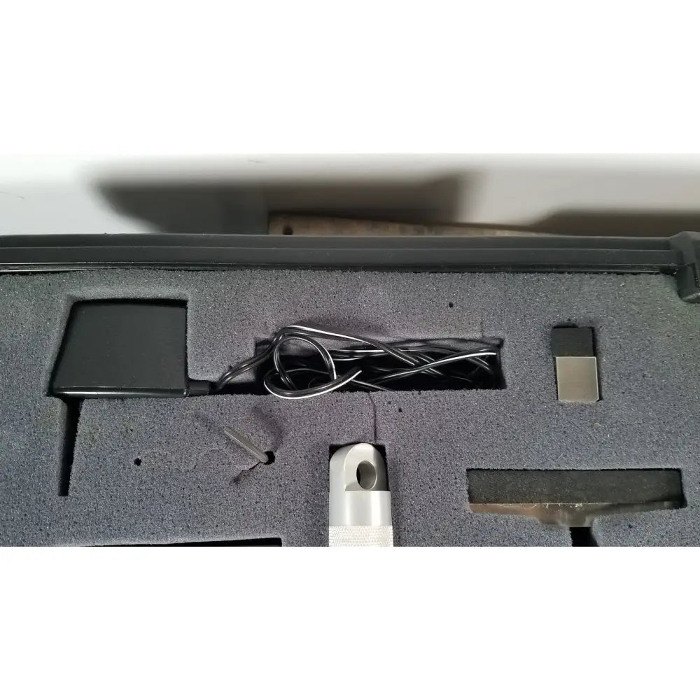 Black rectangular power adapter with coiled silver cable in gray foam for chaltilon csd200 dynamometer reuse medical kit