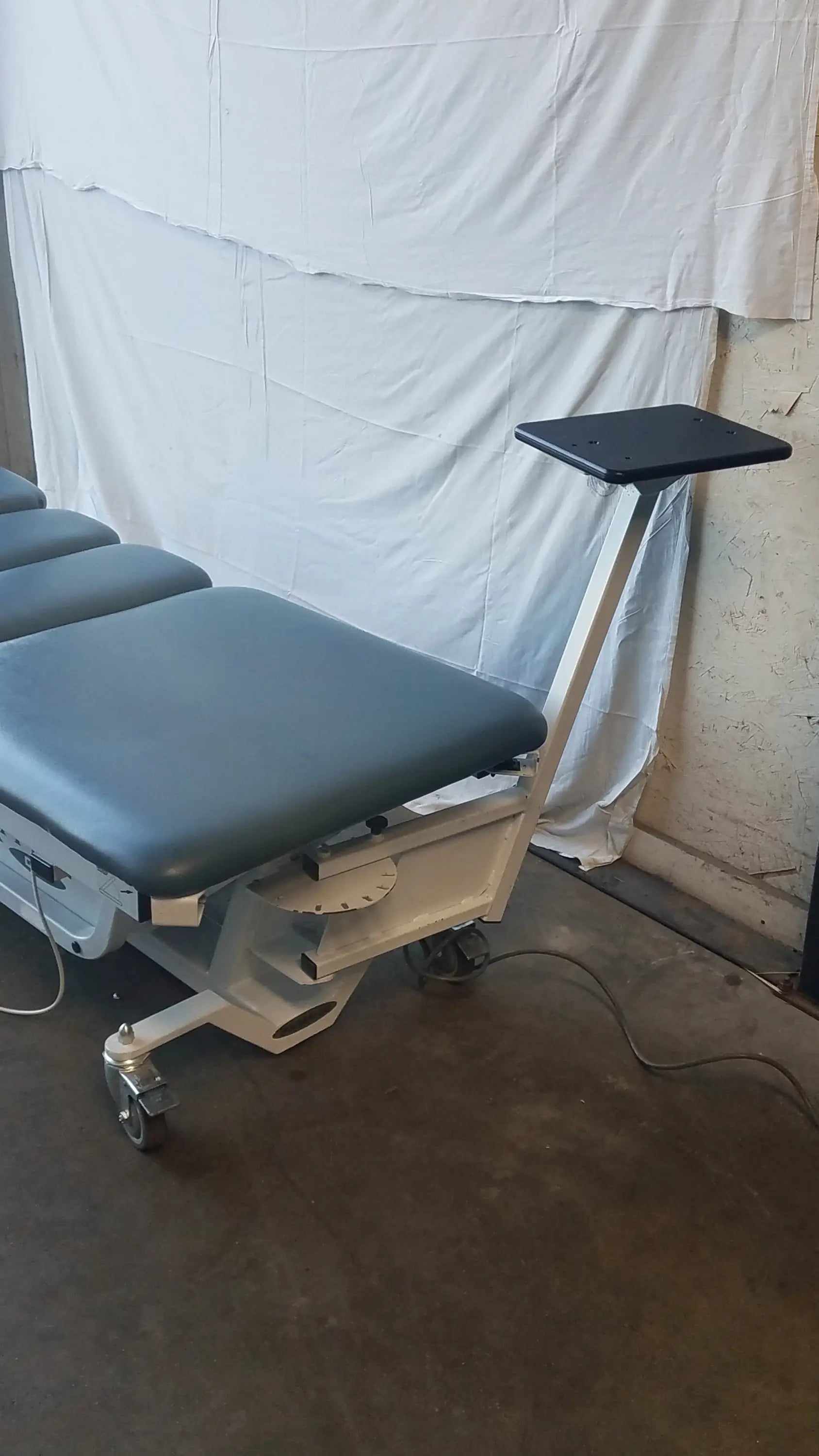 Gray padded Chattanooga triton dts traction table with black adjustable tray and white metal frame on casters for physical therapy equipment