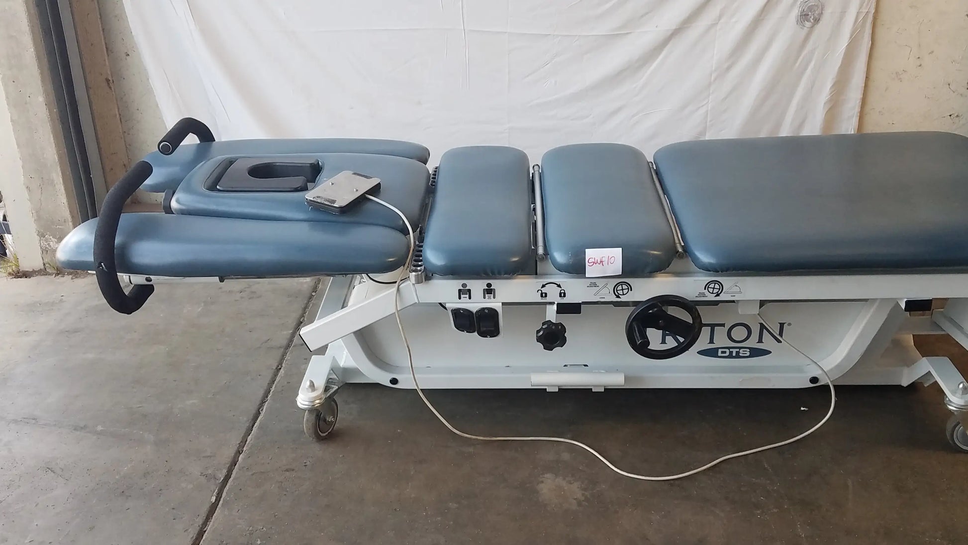 Blue padded Chattanooga TRT-600 Triton DTS table with white metal frame and control panel for physical therapy equipment