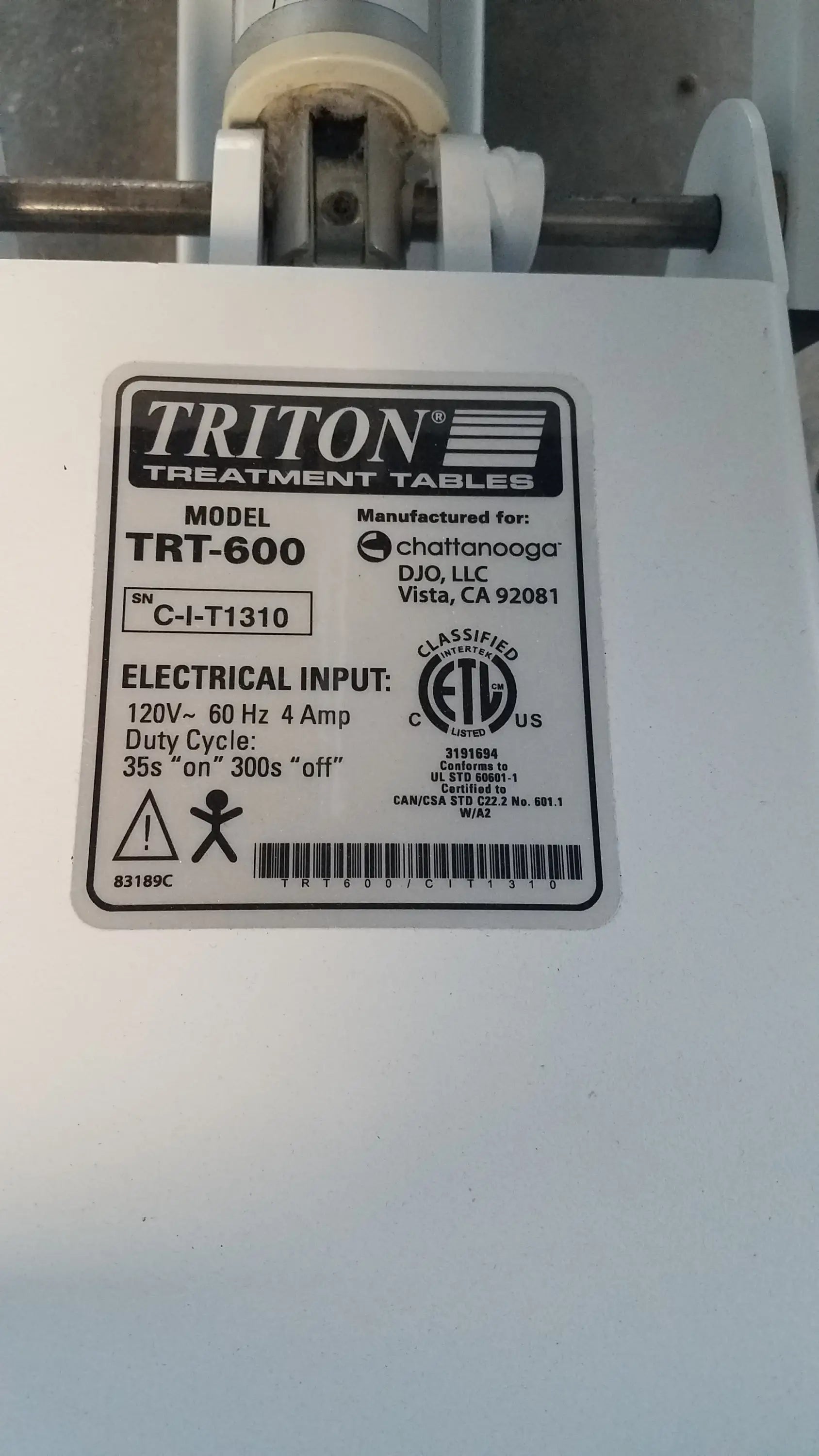 White Chattanooga Triton DTS traction table showing black label with electrical specs and safety certifications on back side