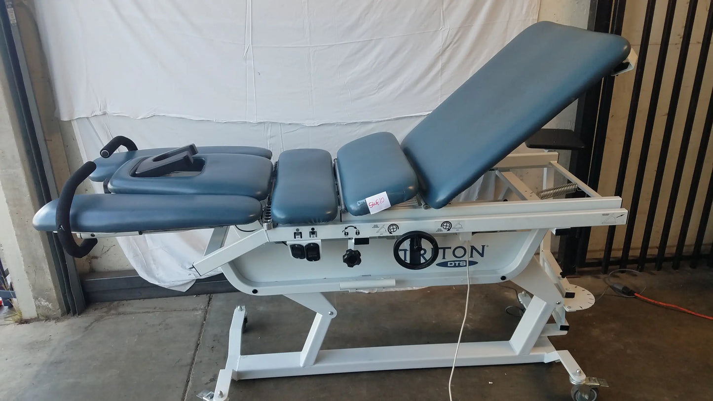 Blue padded adjustable triton dts table with white metal frame for physical therapy equipment use