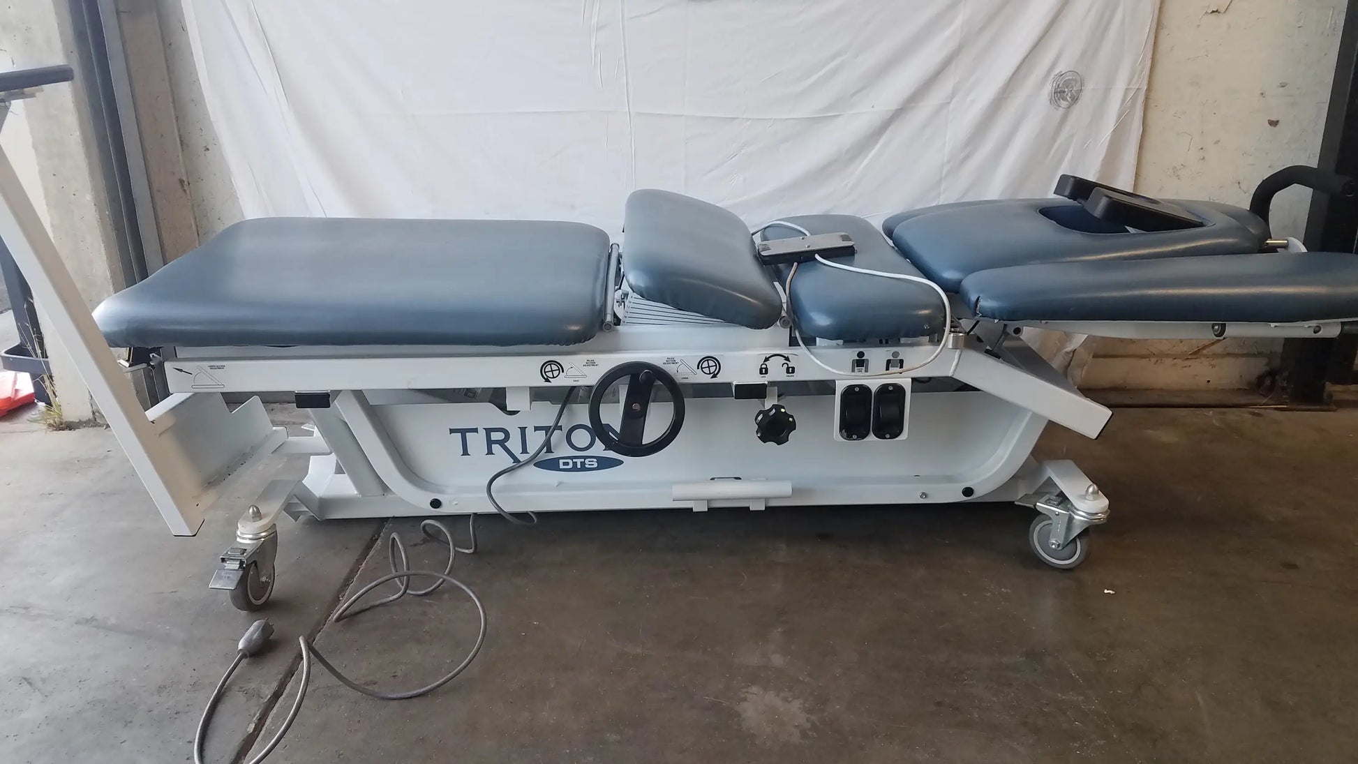 White metal-framed physical therapy equipment triton dts table with gray padded sections and triton dts branding