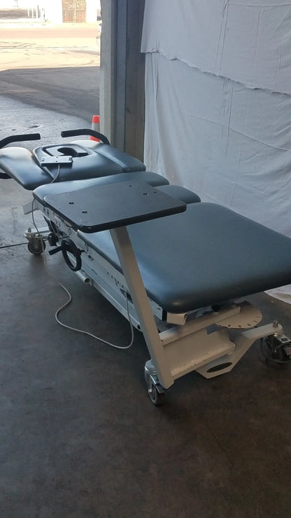 Gray and black adjustable Chattanooga triton dts table with wheeled base for physical therapy equipment use